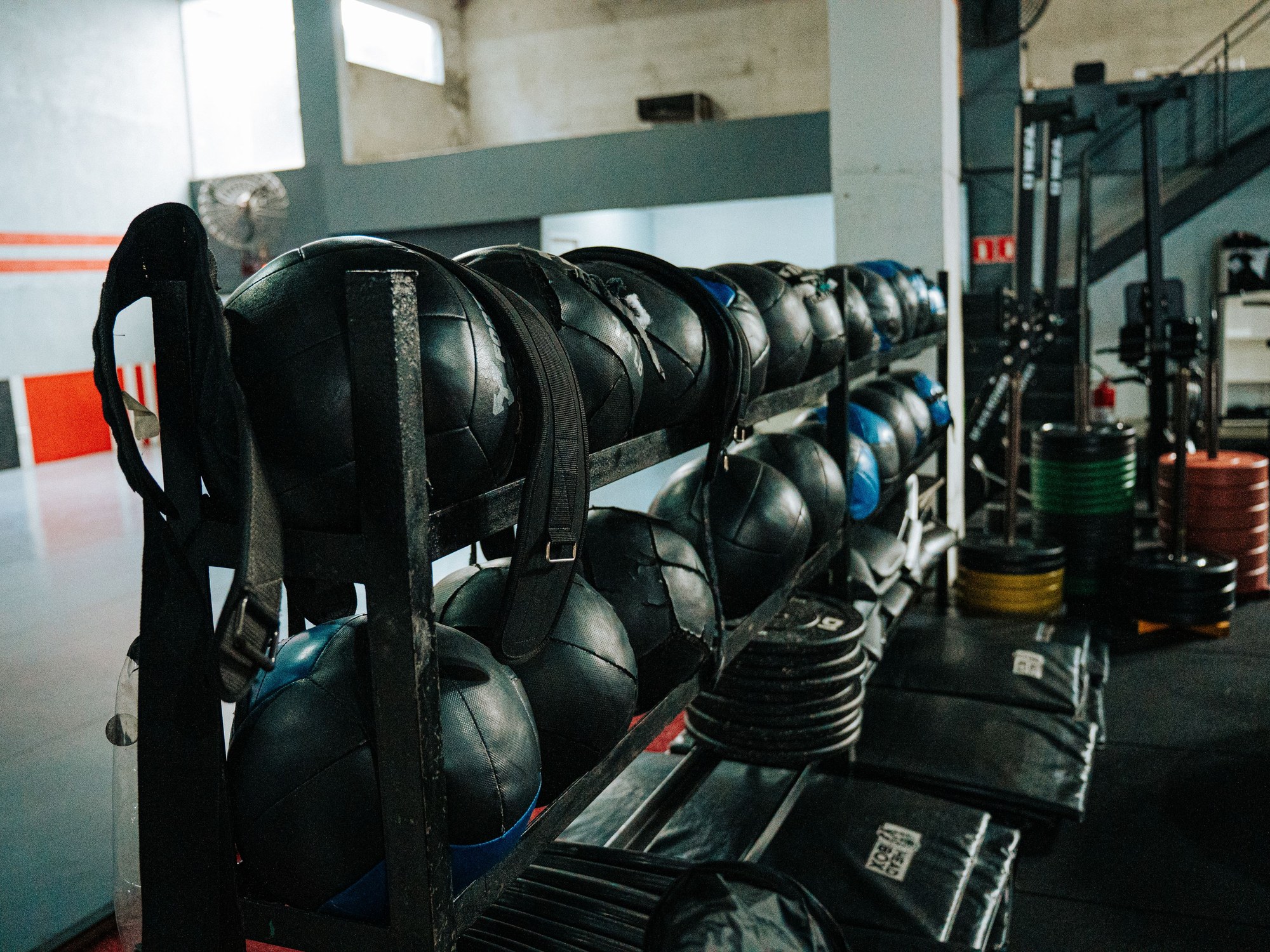 Balones medicinales y discos ordenados en el rack del gimnasio